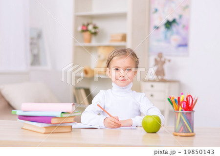 Little girl is sitting at the desk and doing Little girl is sitting at the desk and doing 19850143