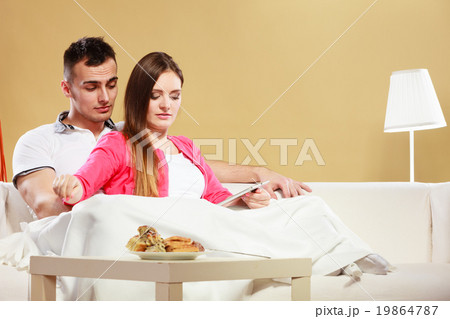 Couple reading ebook relaxing at home on sofa. Couple reading ebook relaxing at home on sofa. 19864787
