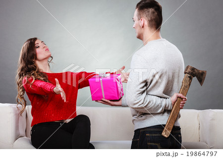 Insincire man holding axe giving gift box to woman Insincire man holding axe giving gift box to woman 19864797