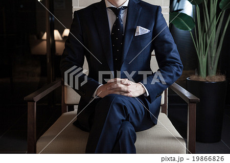 夜のホテルのソファーに座るスーツを着た男性の写真素材