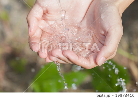 流れる水をすくう女性の写真素材
