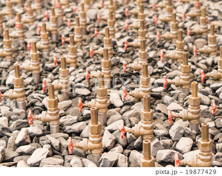 Water taps of fountain court, closeup among gravel. Stack of wat 19877429