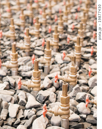 Water taps of fountain court, closeup among gravel. Stack of wat 19877430