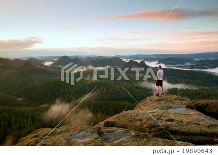 Man in white shirt and black  pants  stand on rock 19890643