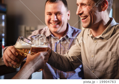 Happy friends drinking beer at counter in pub 19904763