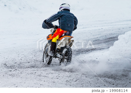 racer motorcycle rides on snow-covered road 19908114