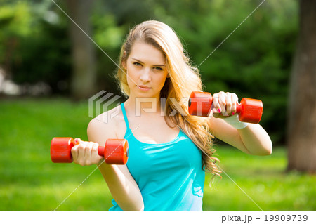 Sports girl exercise with dumbbells in the park Sports girl exercise with dumbbells in the park 19909739