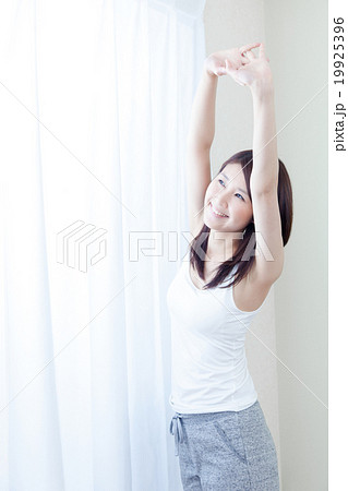 女性 タンクトップ 朝 朝日 カーテン ストレッチ 伸び 腕 の写真素材