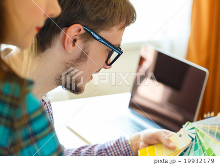 Young colleague - manand woman looking to a color paint palette 19932179