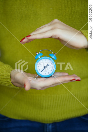 Little blue alarm clock in the hands of woman Little blue alarm clock in the hands of woman 19932206