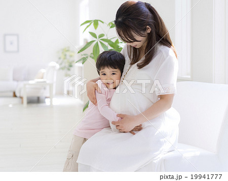 妊娠中の母に抱きつく息子の写真素材