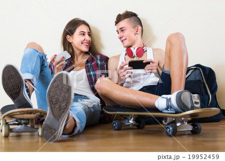 Teenagers sitting on floor with mobile phones . 19952459