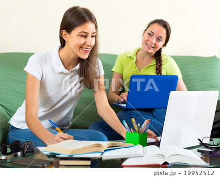 Girls doing homework on couch 19952512