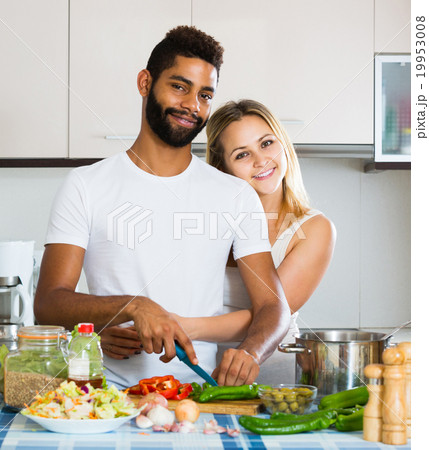 afro man and white woman cooking at kitchen table 19953008