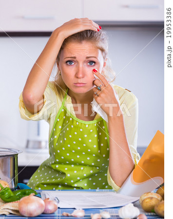 Sad girl with banking statement at home. 19953386