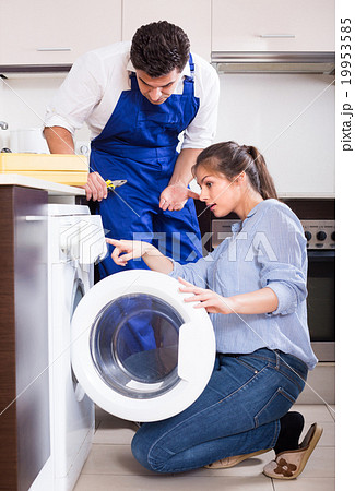 Repairman and woman near washing machine. 19953585