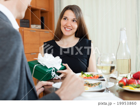 Girl giving gift during romantic dinner 19953860
