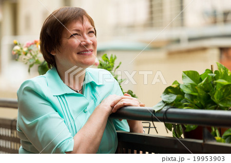 Cheerful senior woman sitting on terrace Cheerful senior woman sitting on terrace 19953903