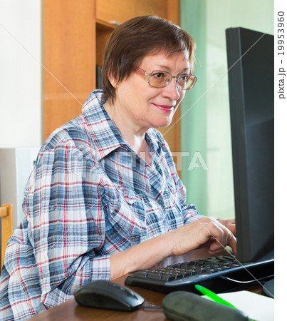 Smiling mature woman using keyboard Smiling mature woman using keyboard 19953960