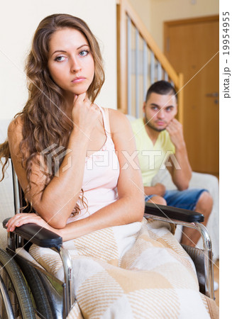 Sad man with girlfriend in invalid chair 19954955