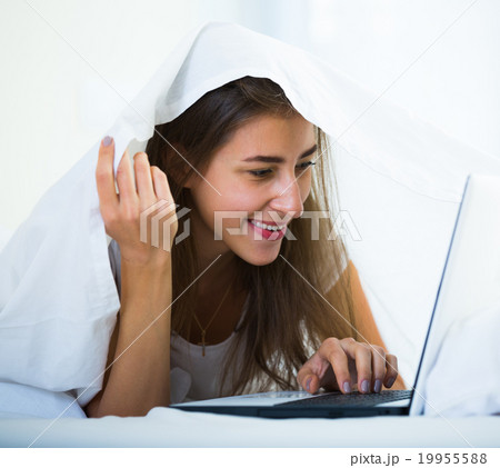 Teenage girl chatting online covered with blanket Teenage girl chatting online covered with blanket 19955588