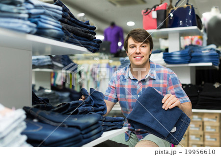 male chooses jeans at clothing store male chooses jeans at clothing store 19956610