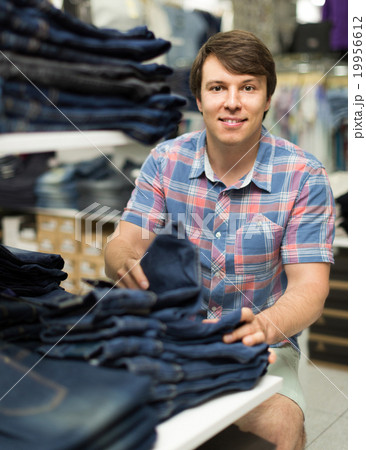 male chooses jeans at clothing store male chooses jeans at clothing store 19956612