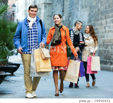 Group of young tourists with purchases Group of young tourists with purchases 19956933