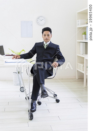 A Businessman Sitting In A Chair With His Legs Stock Photo