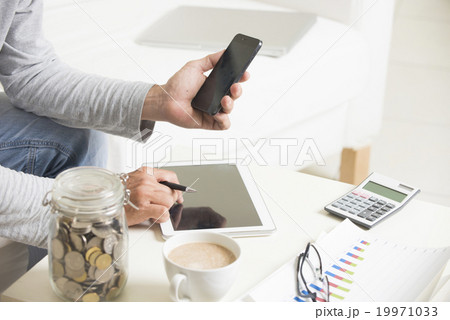 Man doing finance with tablet computer and mobile phone Man doing finance with tablet computer and mobile phone 19971033