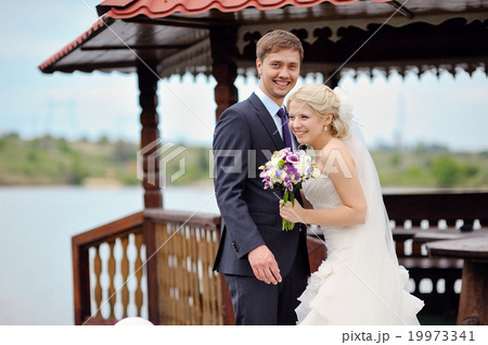 Happy bride and groom on a walk by the lake Happy bride and groom on a walk by the lake 19973341