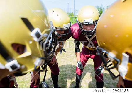 American Football players at strategy huddle 19991188
