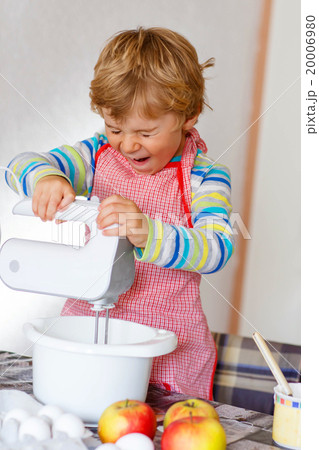 Funny blond kid boy baking apple cake indoors 20006980