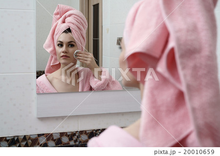 Beautiful woman cares for skin in mirror Beautiful woman cares for skin in mirror 20010659