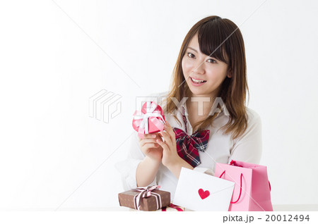 たくさんのプレゼントを前にプレゼントを持つ女性 女子高校生 喜ぶプレゼント選びの写真素材