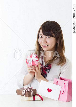 たくさんのプレゼントを前にプレゼントを持つ女性 縦構図 女子高校生 喜ぶプレゼント選びの写真素材