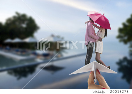 Couple ride paper plane on blur beach pool 20013273