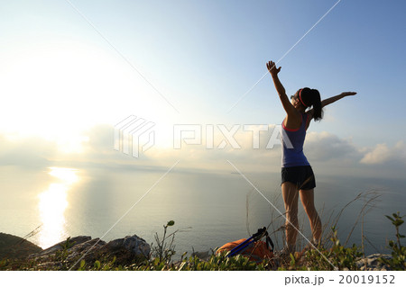 cheering young woman backpacker at sunrise seaside mountain peak cheering young woman backpacker at sunrise seaside mountain peak 20019152