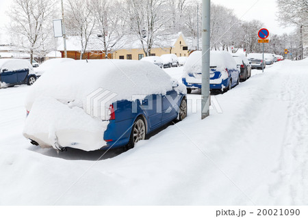 Cars covered with snow parked along snowy street 20021090