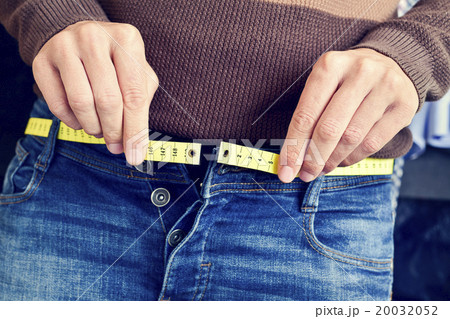 young man trying to fasten his trousers 20032052