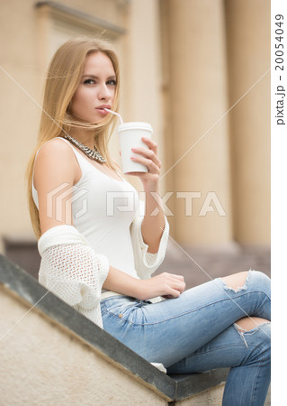 stylish woman drinking coffee to go in a city 20054049