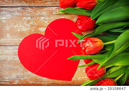 close up of red tulips and paper heart shape card 20108647