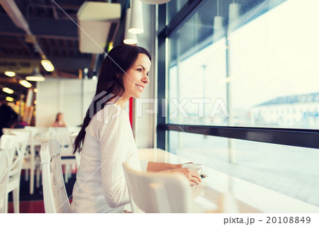 smiling young woman drinking coffee at cafe 20108849