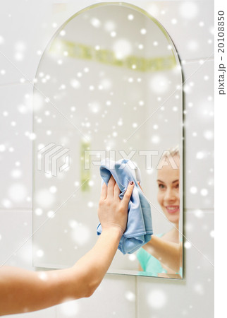 close up of happy woman cleaning mirror with rag 20108850