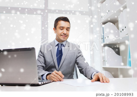 smiling businessman with laptop and papers 20108993