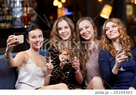 women with champagne taking selfie at night club 20109303