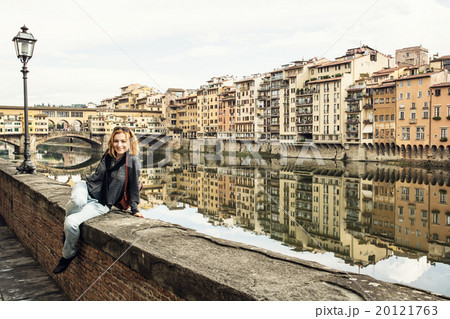 Young tourist woman is sitting on the wall in front of the Ponte 20121763