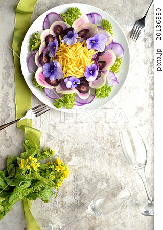 大根と紫色のエディブルフラワーのサラダと菜の花の花束の写真素材