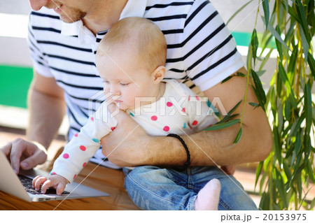 Young father with his baby working or studying on laptop 20153975