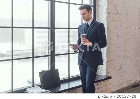 Businessman in suit holding smartphone standing 20157729